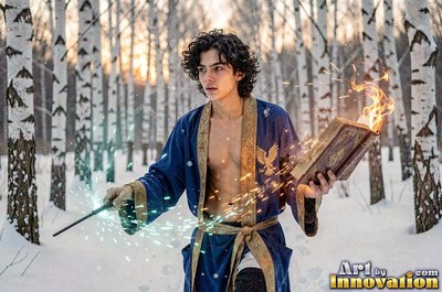 Standing in a snowy forest, a young man in a blue robe holds a burning book