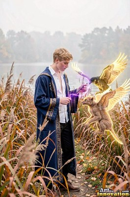 A young man in a blue robe points a wand by a lake