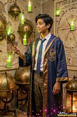 Young man in a blue robe holds a wand near green candles