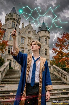 Standing on castle steps, a young man in blue robes raises a wand