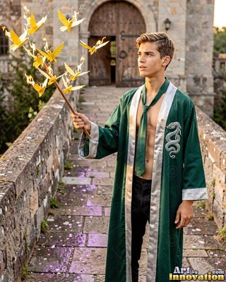 A young man holds a burning branch in an open green gown in soft daylight