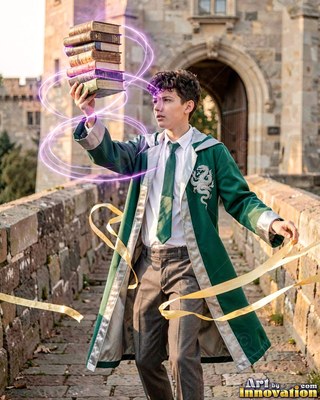 Wearing a green wizard robe, a young man floats a stack of books along a stone castle bridge