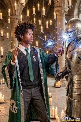 Young man in green wizard robes casts sparks at a suit of armor