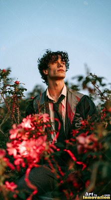 In a garden of red flowers, a young man in a school uniform looks up at the sky