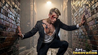 An injured man in a torn suit leans against brick alley walls
