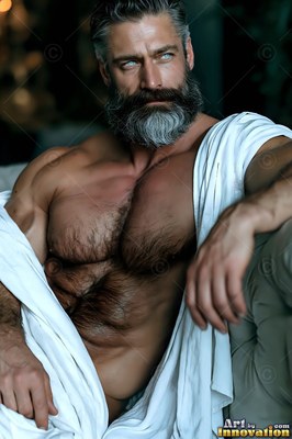 Reclining indoors, a broad-shouldered man who has a beard rests wrapped in a white cloth