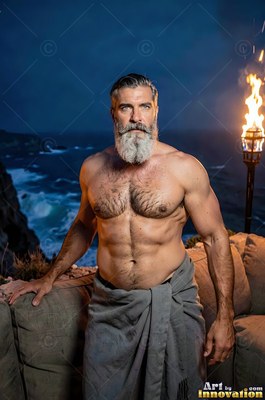 A man with a beard stands on a terrace by a torch under the dark blue night sky