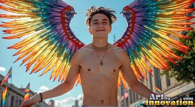 A smiling shirtless man spreads rainbow wings of feathers in the bright sunlight