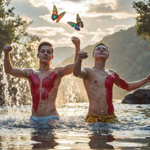 The Beautiful & Handsome Men Art Collection, A high-resolution photograph of two handsome best friends, half submerged in water, covered in body paint. Butterfly's flying about, as they spend time together, with a smile on their faces.