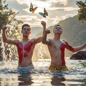 The Beautiful & Handsome Men Art Collection, A high-resolution photograph of two handsome best friends, half submerged in water, covered in body paint. Butterfly's flying about, as they spend time together, with a smile on their faces.