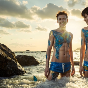 The Beautiful & Handsome Men Art Collection, A high-resolution photograph of two handsome best friends, half submerged in water, covered in body paint. Butterfly's flying about, as they spend time together, with a smile on their faces.