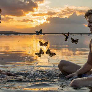 The Beautiful & Handsome Men Art Collection, A high-resolution photograph of two handsome best friends, half submerged in water, covered in body paint. Butterfly's flying about, as they spend time together, with a smile on their faces.