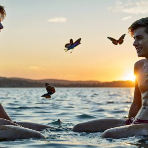 The Beautiful & Handsome Men Art Collection, A high-resolution photograph of two handsome best friends, half submerged in water, covered in body paint. Butterfly's flying about, as they spend time together, with a smile on their faces.