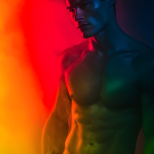 AI-generated art capturing men in a rainbow of colors creates a striking visual impact, blending surreal, vibrant, and high-fashion elements. Featuring artwork of beautiful, shirtless, muscular men embellished with or surrounded by a vibrant rainbow palette, evoking themes of pride, vitality, and artistic expression.