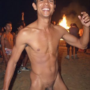 Bad Boys Naked Beach Party II. A full-body composition of a nude young man standing near a crackling bonfire, on a serene moonlit night at the beach. The gentle glow of the flames, flickers across his shinny wet body, catching his contours, and highlighting his muscular physique and handsome face. People everywhere partying, dancing to the music, having a good time together, naked, and free.